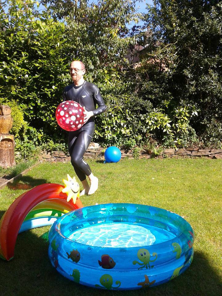 Alex in a wetsuit with a beachball and paddling pool